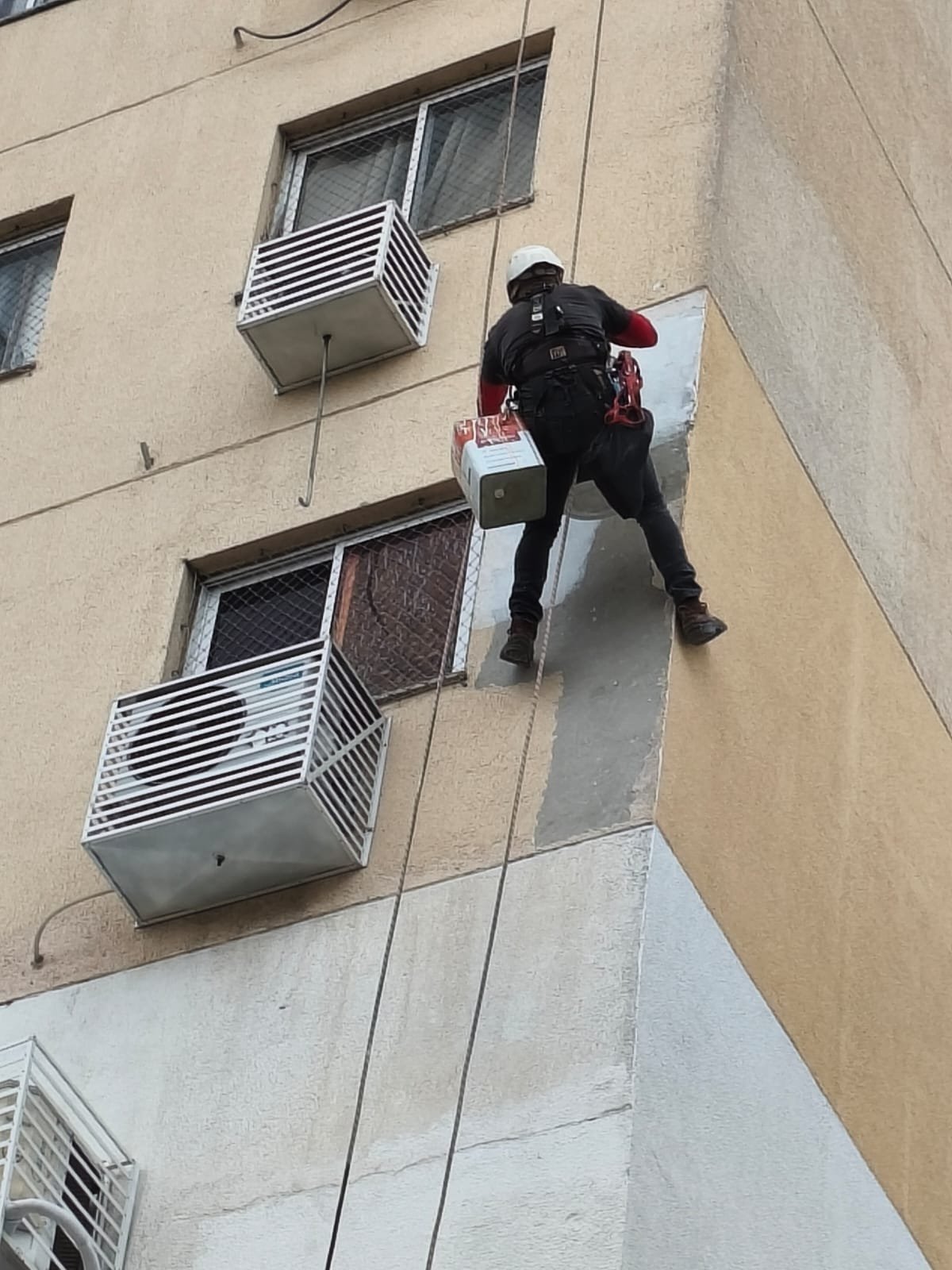 Profissional trabalhando na quina da fachada por acesso por corda